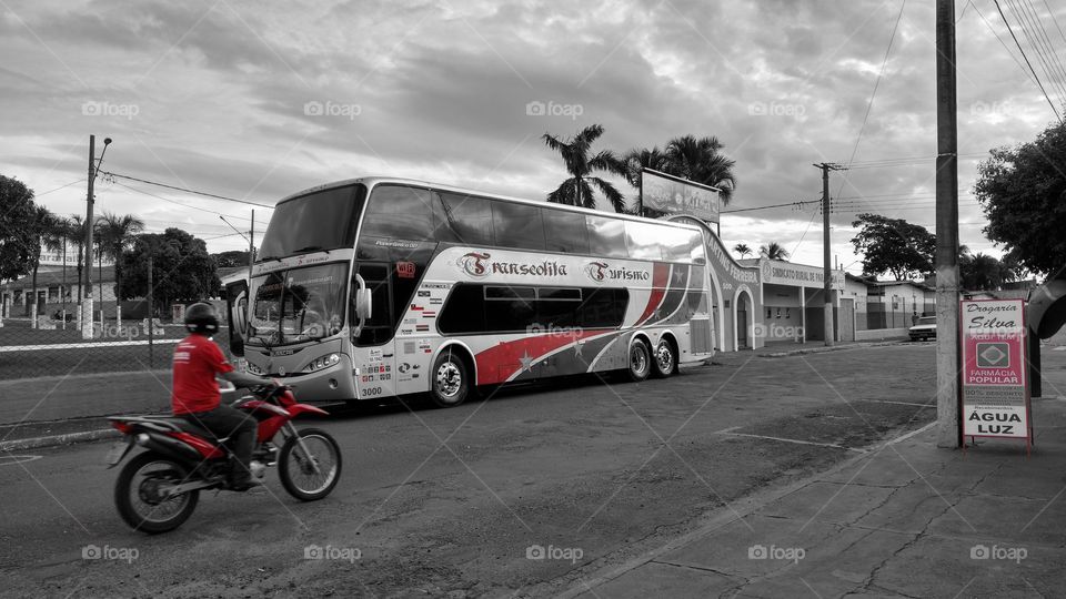 Homem motociclista e ônibus na rua.