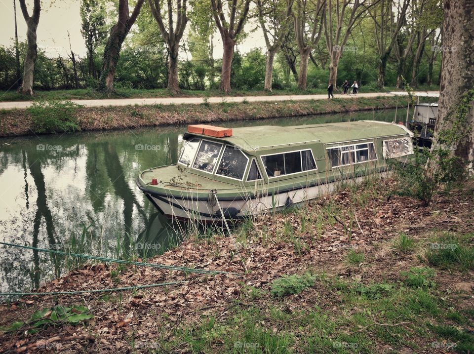 Trees along and a boat on a canal in Toulouse, France 