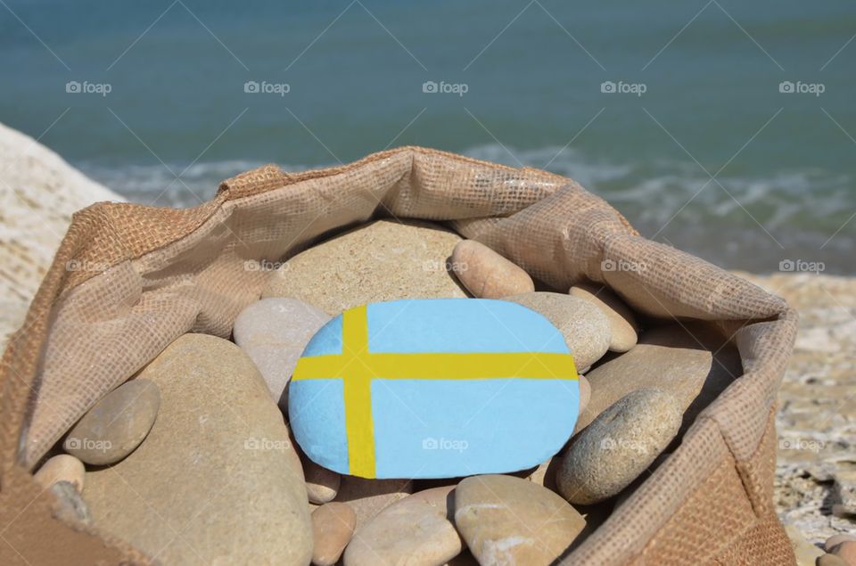 Swedish flag on a stone in a bag of pebbles