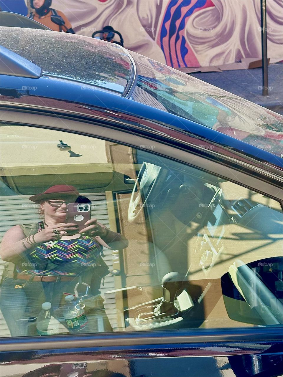 Checking myself out in a mirrored car window on “Jefferson St” off “B’way” in “Bushwick”, Bklyn I take the larger picture incl. the sassy jazzy cool Latin art mural that once again reflects in the metallic blue car roof. 2024. Hypnotic Productions