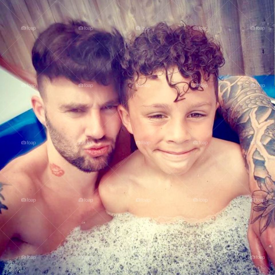 Modern father and son cooling off in a paddling pool in the summer heat