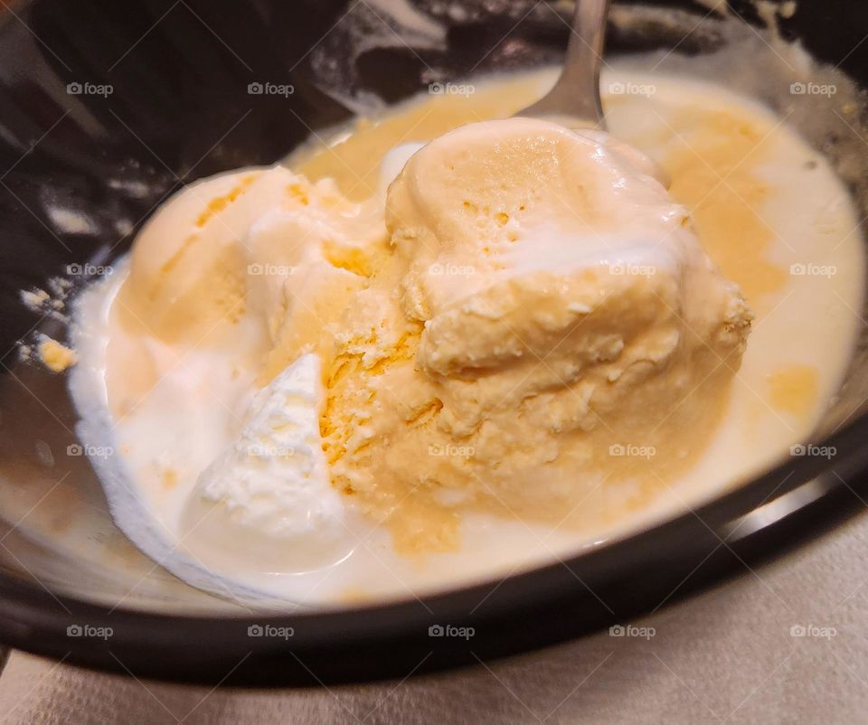 bowl of tasty cold orange and vanilla ice cream scoops melted into soupy puddle from the Summer heat