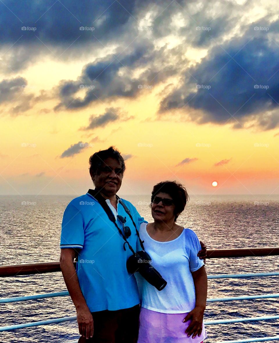 Senior couple with camera on boat in sea during sunset