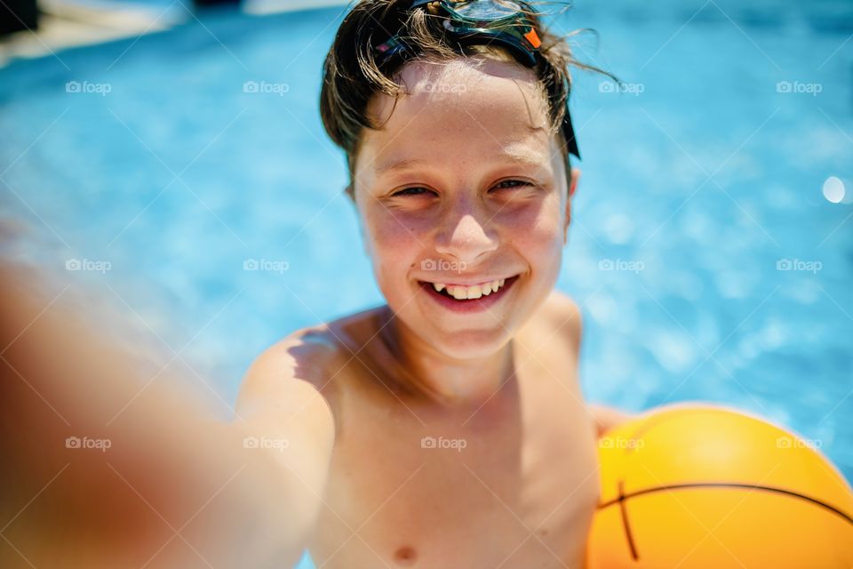 boy makes funny selfie in the pool