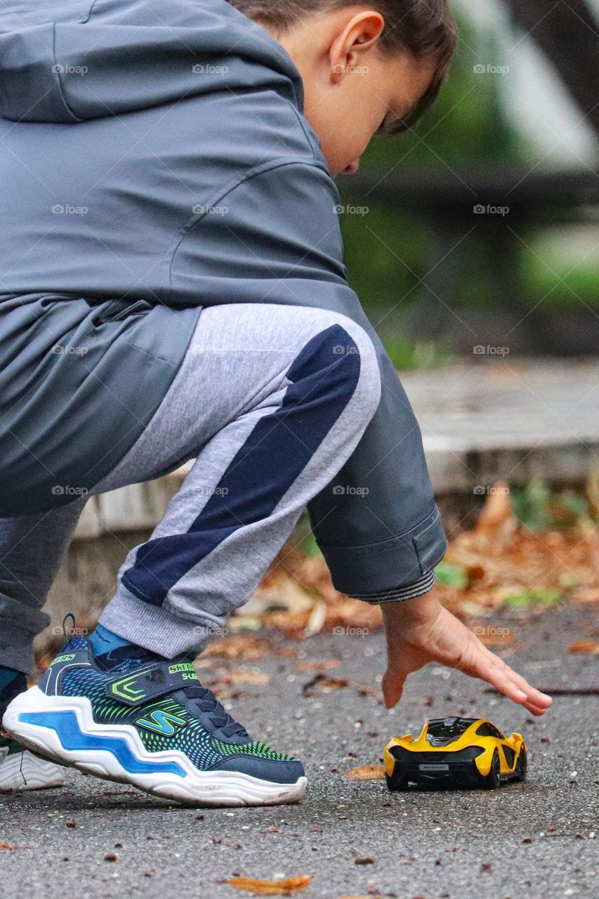 A boy playing with a toy car