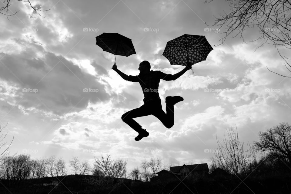 Men jumping in air holding umbrella
