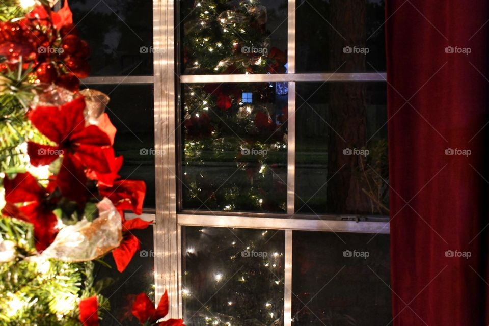 A reflection of a lighted Christmas tree on the window