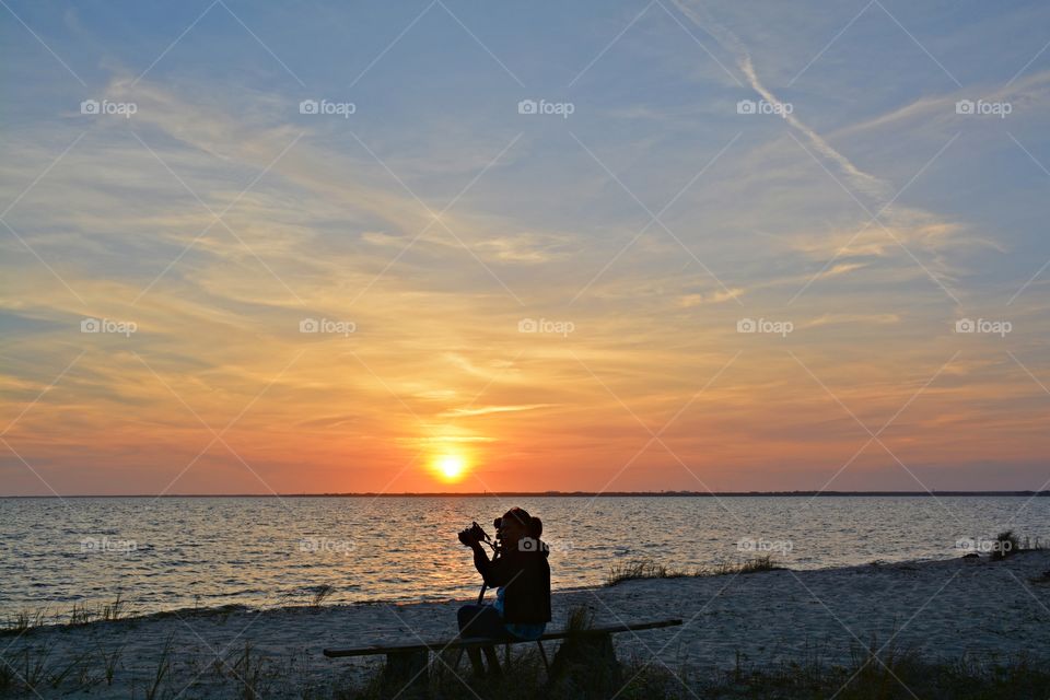 A lady photographer adjusts her camera as she gets ready to photograph a magnificent sunset