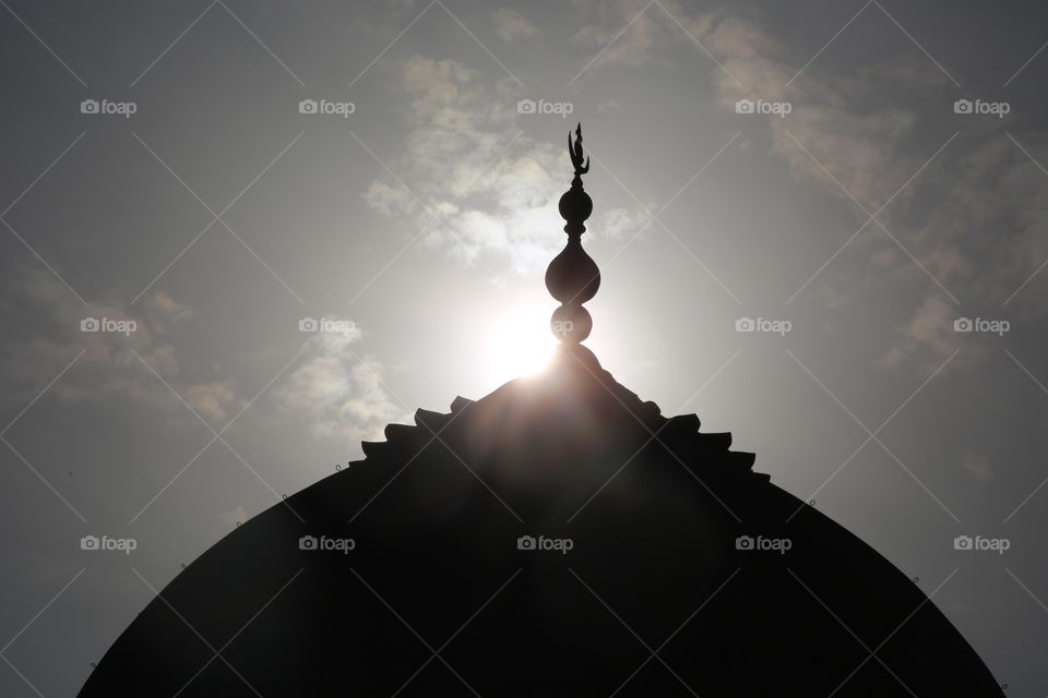 The top of the Taj Mahal backlit by the setting sun.