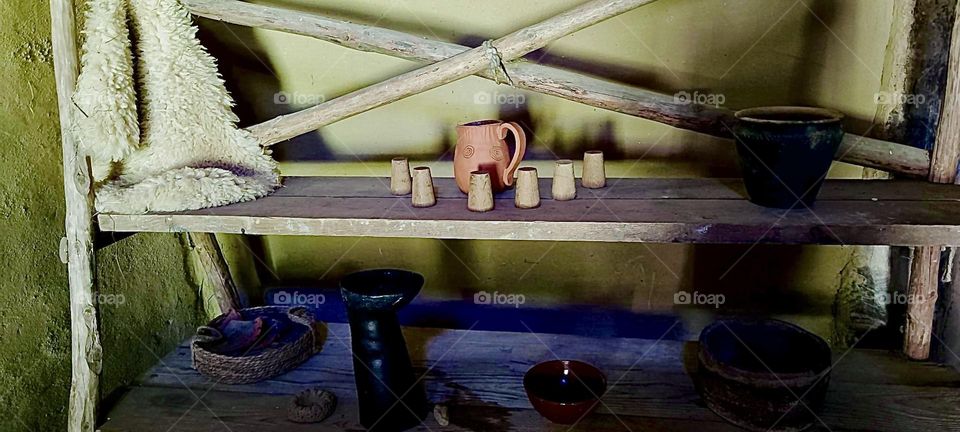 A raw ceramic pitcher and short cups are on the table in the farmhouse at “Keltendorf Gabreta”, a newly erected Celtic village after ancient models near the small town of “Ringelai” in “Bavaria”, Germany.. 2023. Hypnotic Productions