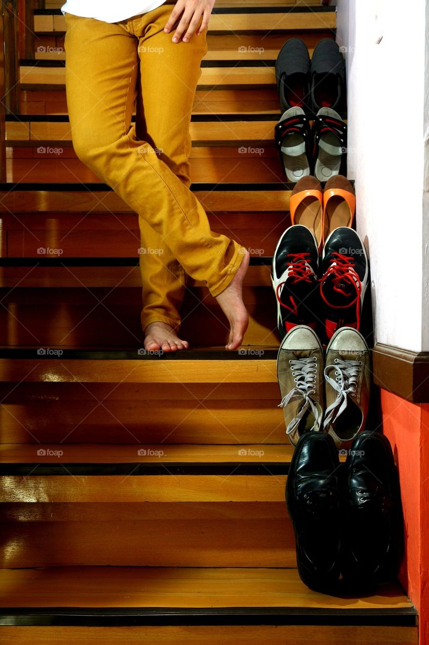 person standing beside shoes on staircase