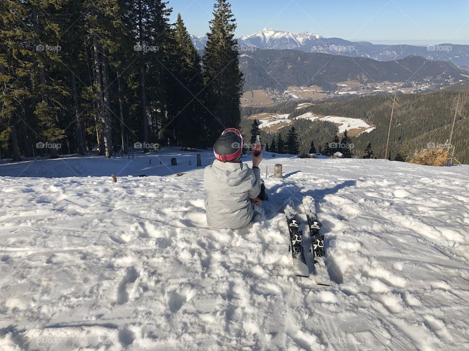 A girl with a bottle of Cola having a break after skiing