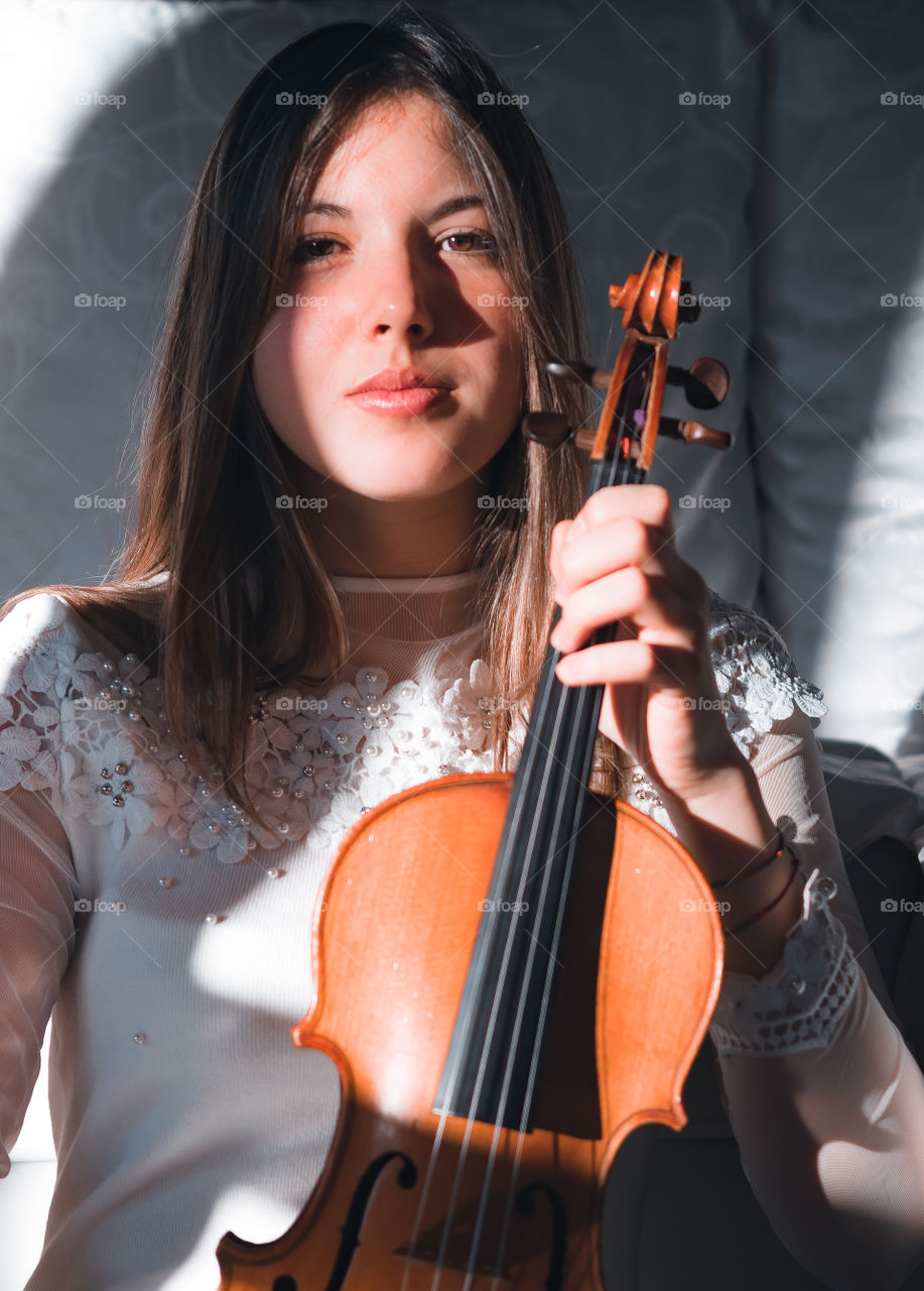 Girl holding a violin in the house