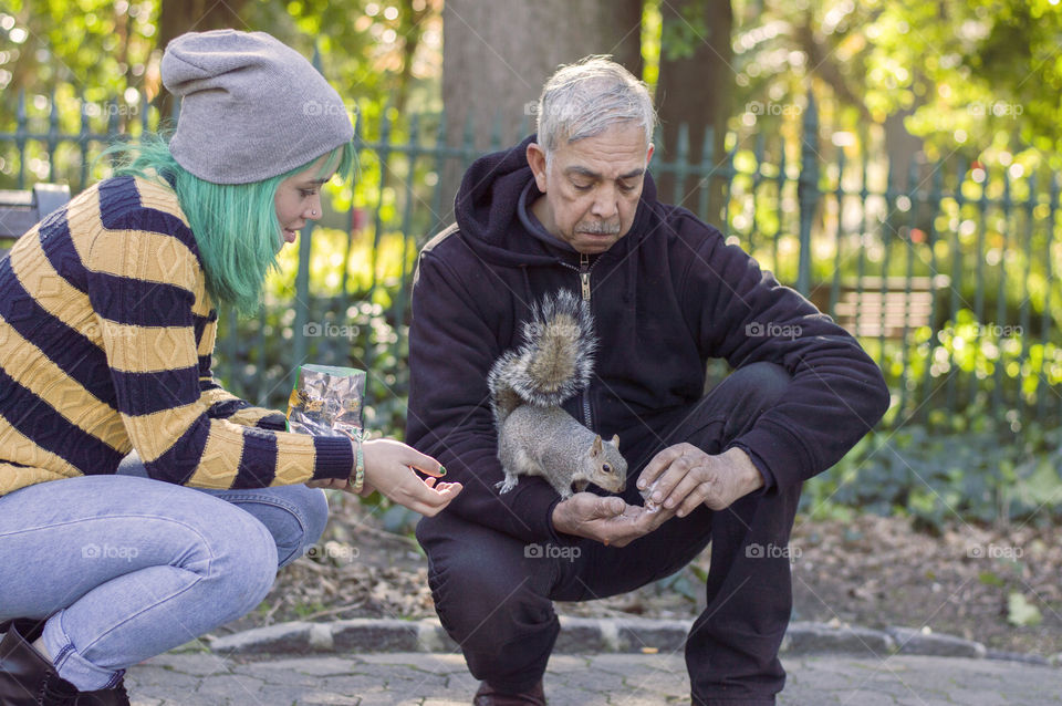 Alternative girl and old man feeding a squirrel