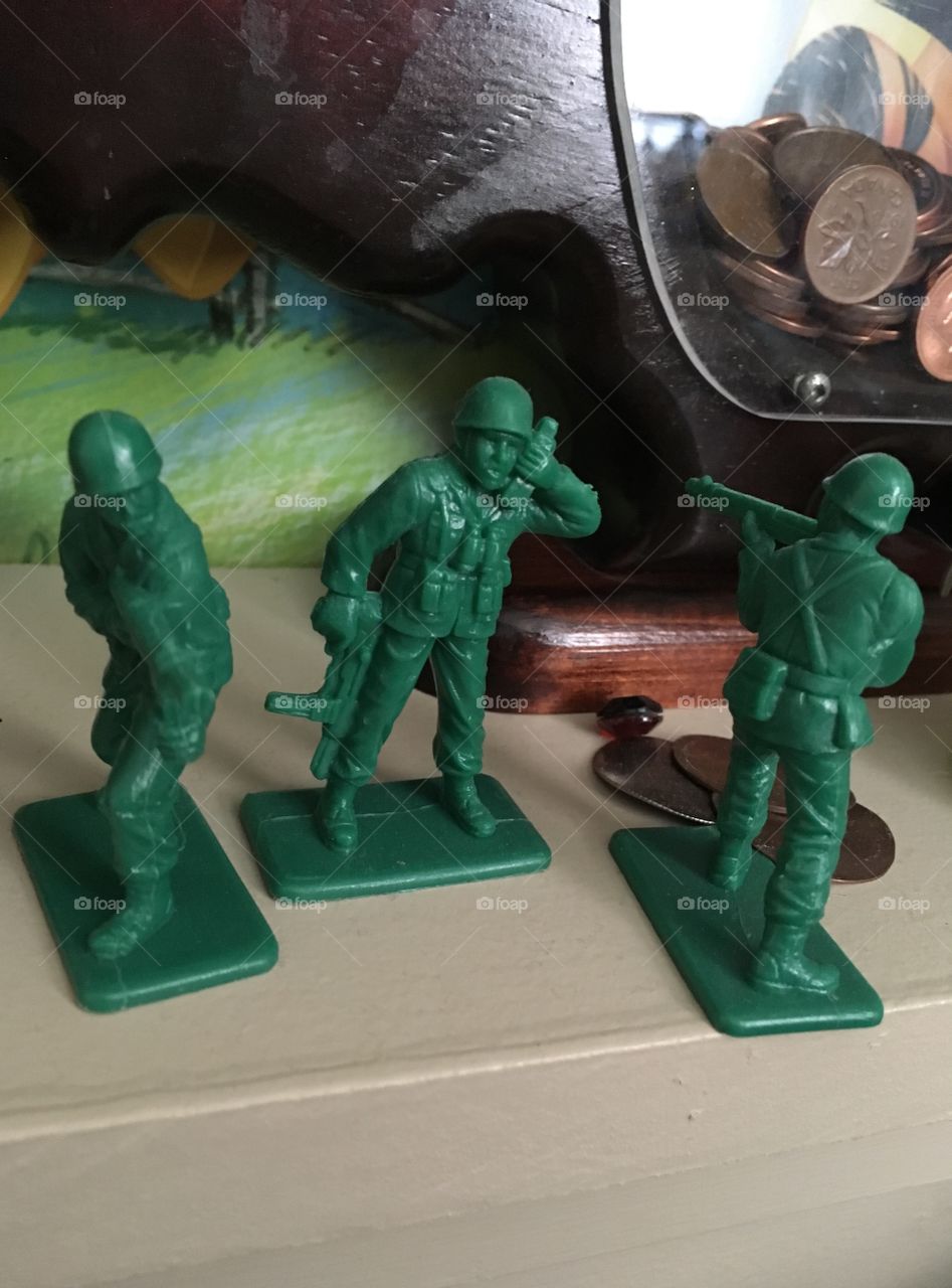 Green toy soldiers on shelf in front of piggy bank. Child's room. 