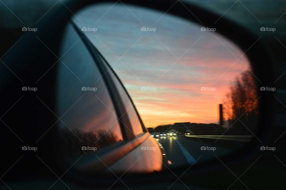 Colorful sunrise in the wing mirror in Alfa Romeo 159 car on the expressway in Poland
