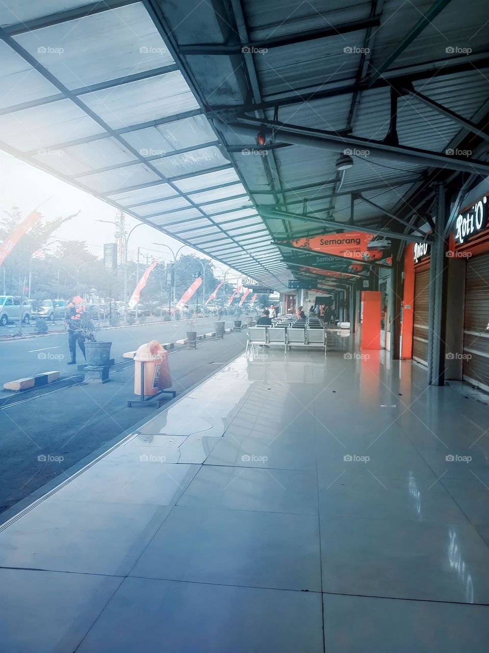 Wide sidewalks in front of several shops with protective roofs, and people were walking in the distance