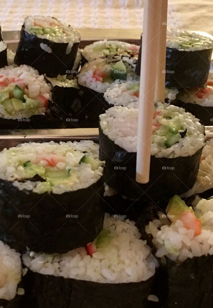 Sushi rolls crab meat, avocado, cucumber maki closeup with chopsticks 