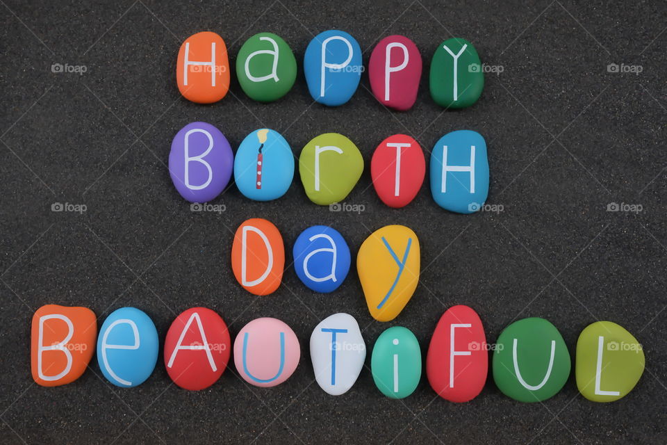 Happy Birthday Beautiful, creative composition text with multi colored stone letters over black volcanic sand