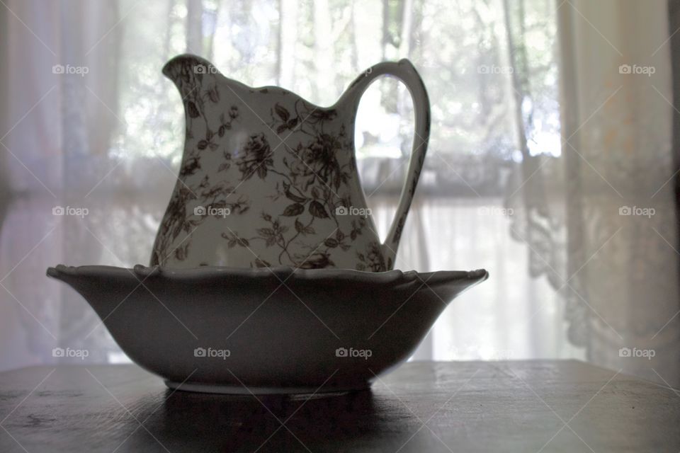 Minimalistic Snaps - backlit pitcher and basin on a wooden surface 