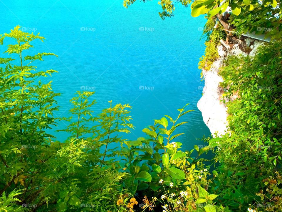 The view of the blue sea is seen from the top of the rock cliff