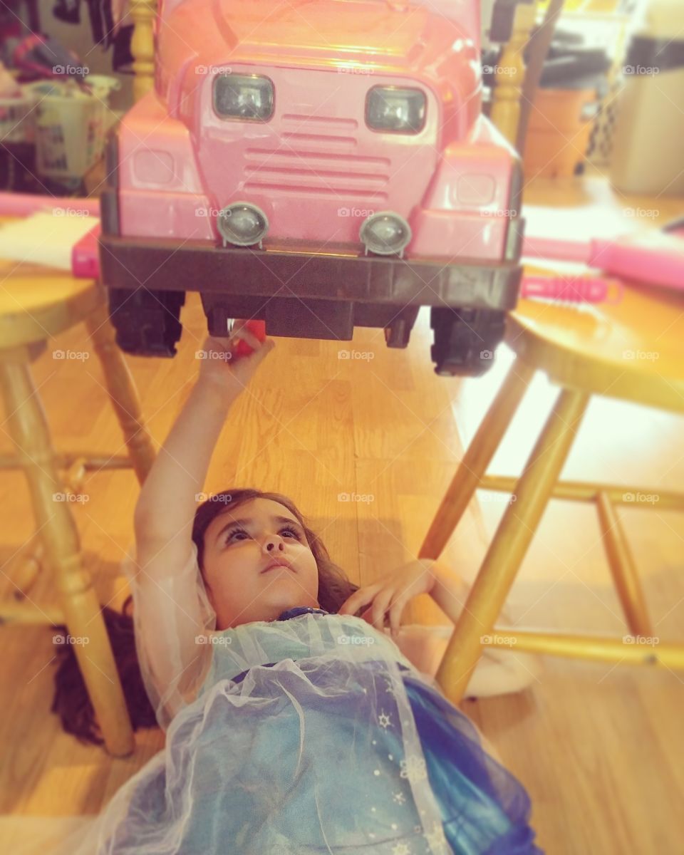 Small girl repairing toy car in house