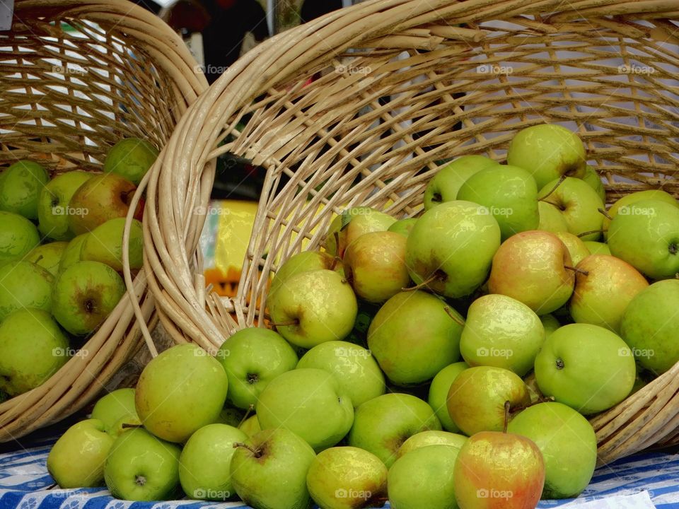 Green apples on wicker basket in market