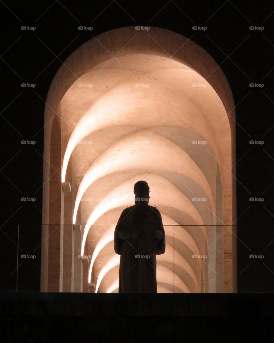 statue silhouette under a series of arches