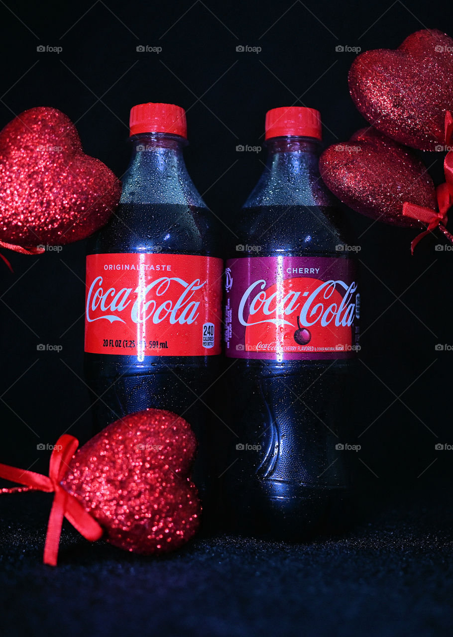 Close up shot of coke cola with valentine hearts in a black background in studio.