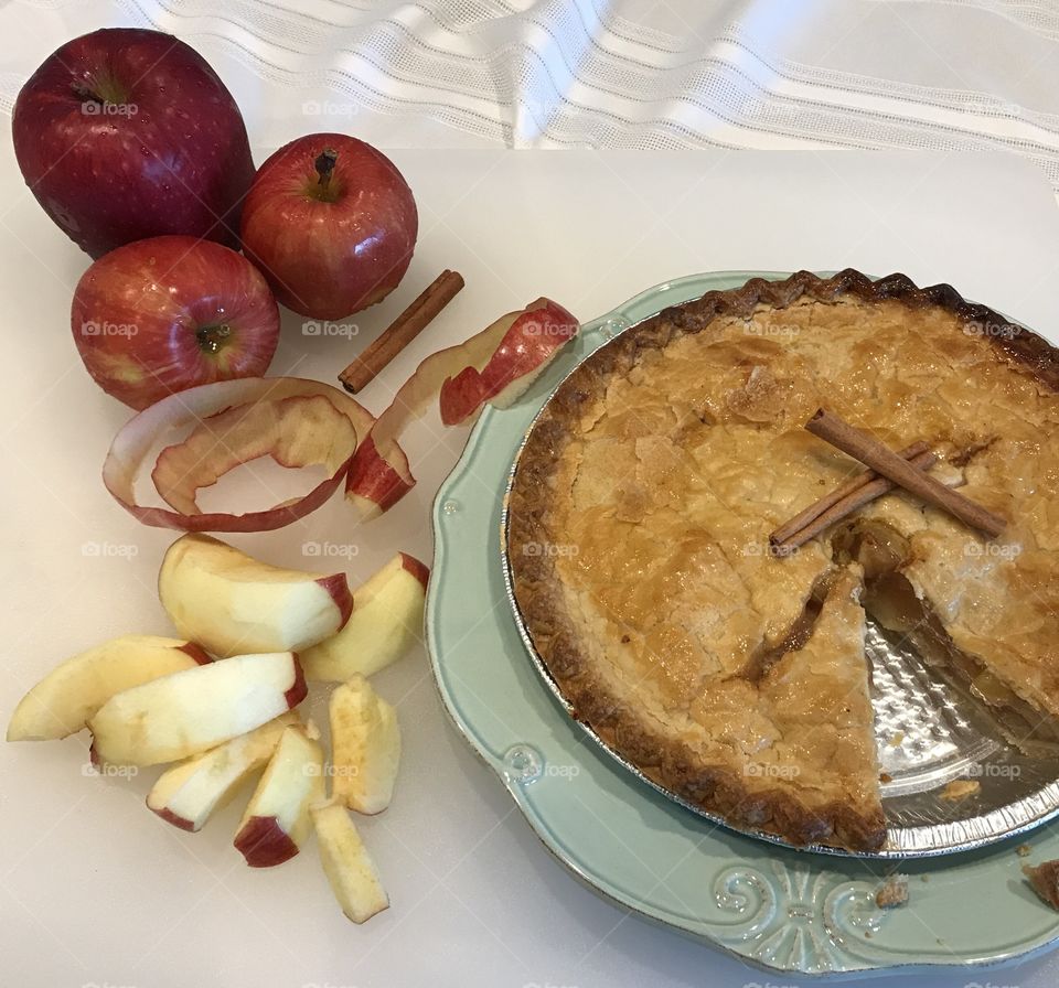 Sliced apple pie with cinnamon sticks and red apples 