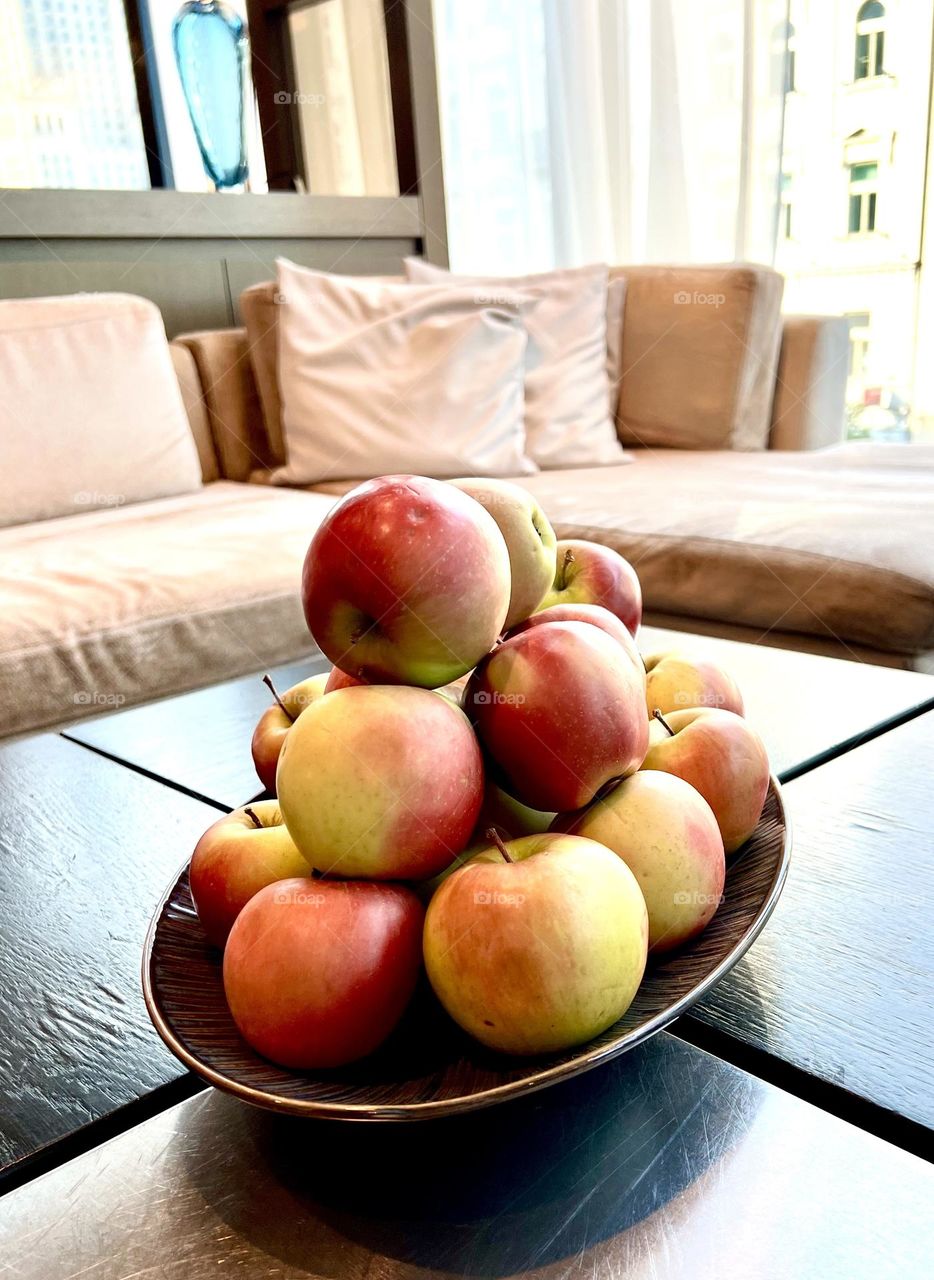 The photo shows a plate of apples. The apples look fresh and appetizing, with glossy skin that reflects light. Their rich colors range from bright red to green, creating a beautiful contrast.