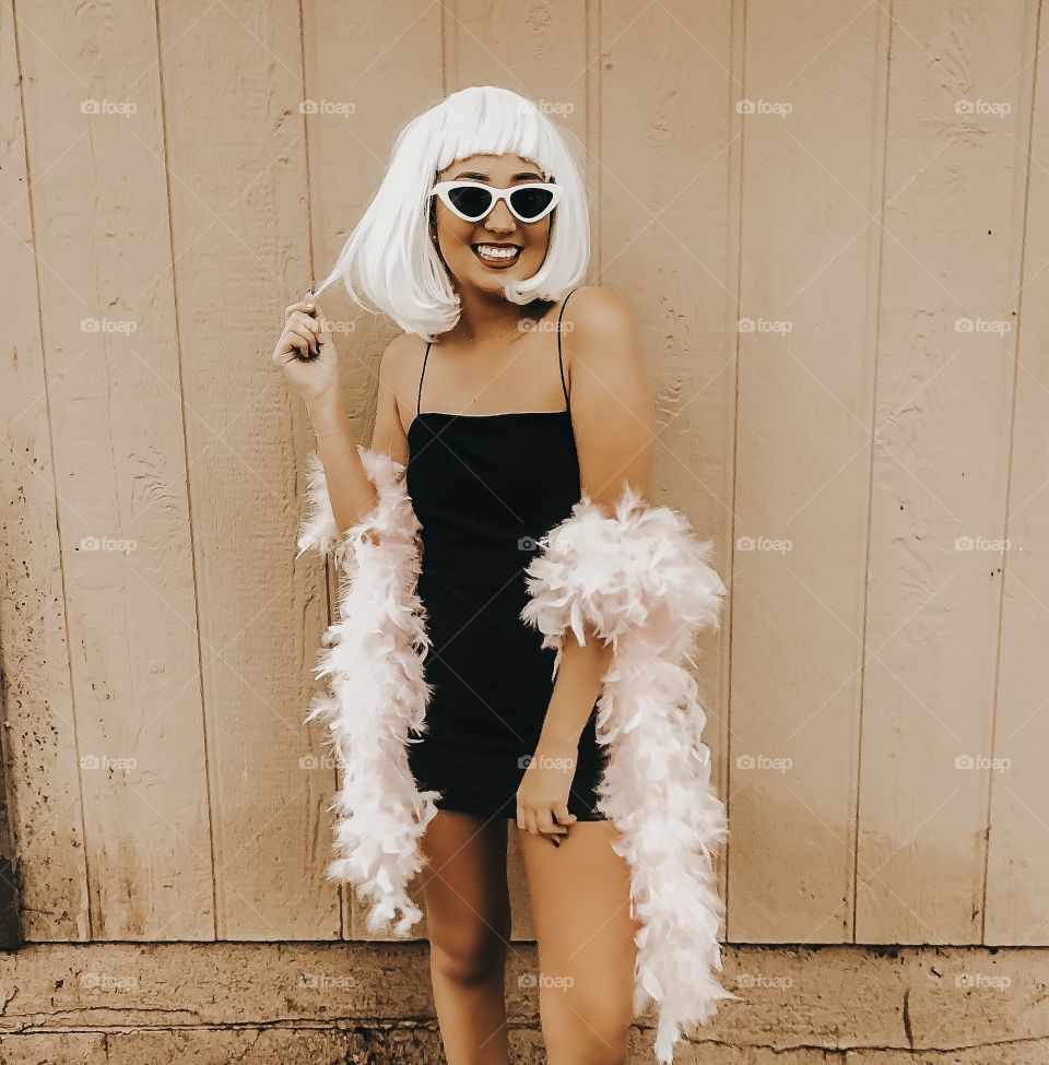 Young girl posing in a fun wig and pink boa with retro sunglasses.