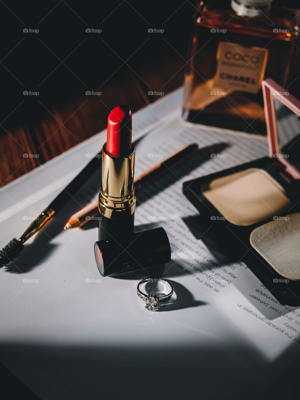 Red lipstick with make up cosmetics and tools on a table.