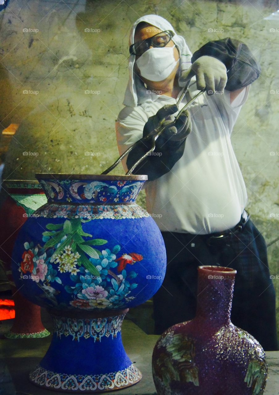 Firing an enamel vase. China, a worker putting a vase in the kiln
