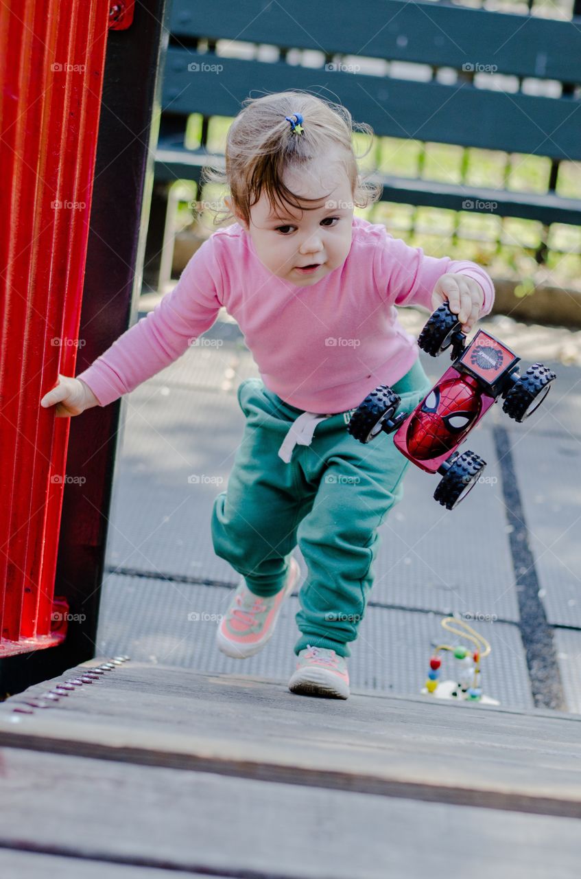 Cute little girl playing with toy car at outdoors