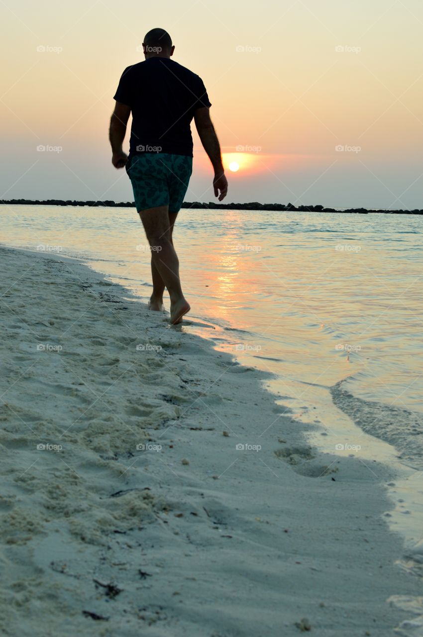 Walk on tropical beach at sunset