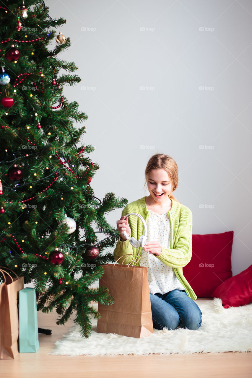 Teenage girl sitting in front on christmas tree