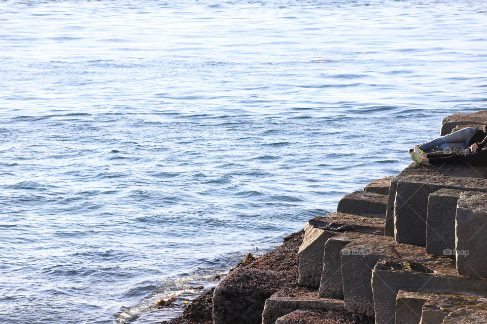 People sitting on stone steps by the ocean 