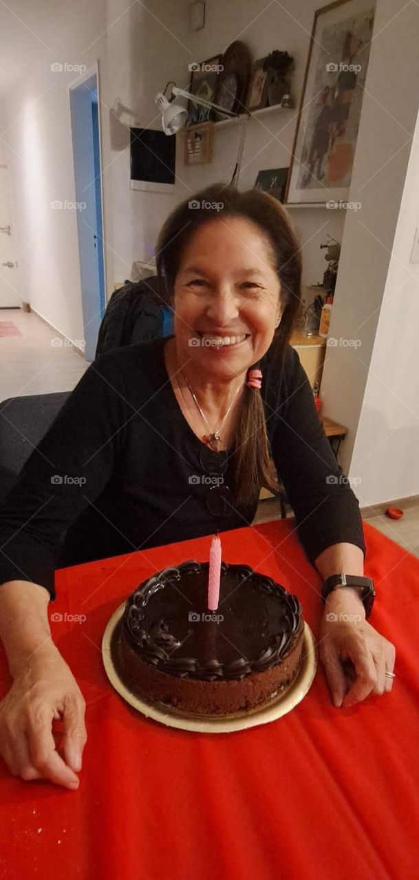 Happy,  smiling woman,  with a vegan birthday cake with a pink candle.