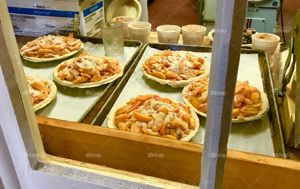 Yummy peach pies being made behind the windows at a bakery