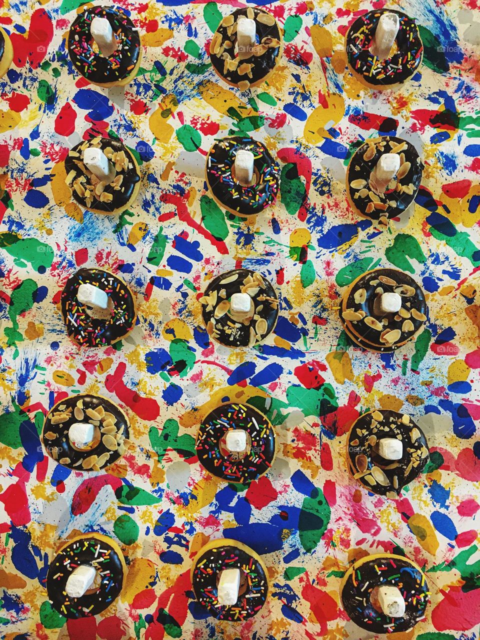 Variety of donuts hanging on colorful abstract patterns spread across the background, creating a vivid and lively scene. 