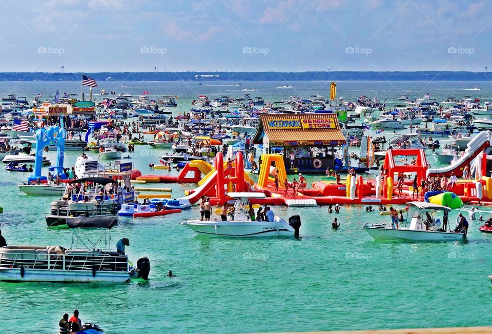 Large crowds are observed all over Crab Island a Destin seashore. These people come enjoy themselves in the beach at this period of the year. People of all ages and sexes are seen swimming and playing with water sports. Boats are parked everywhere.