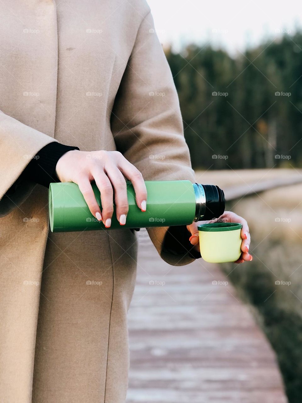 Unrecognisable woman holding a green thermos in her hands
