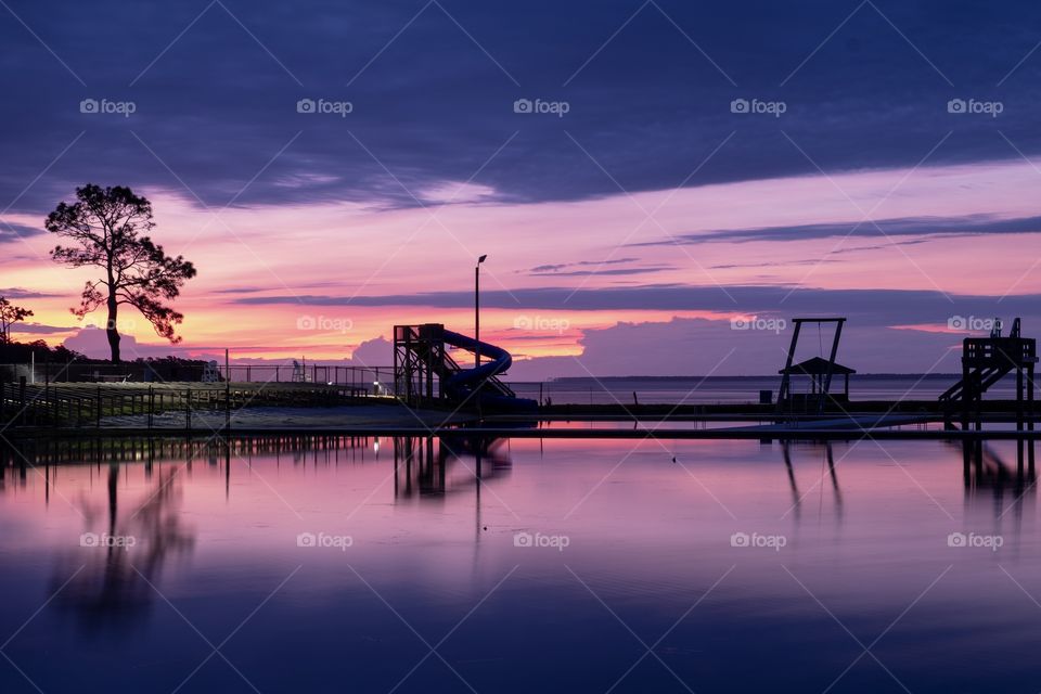 Colorful sunrise over a pond by a water slide at a park along the Neuse River estuary in North Carolina. 