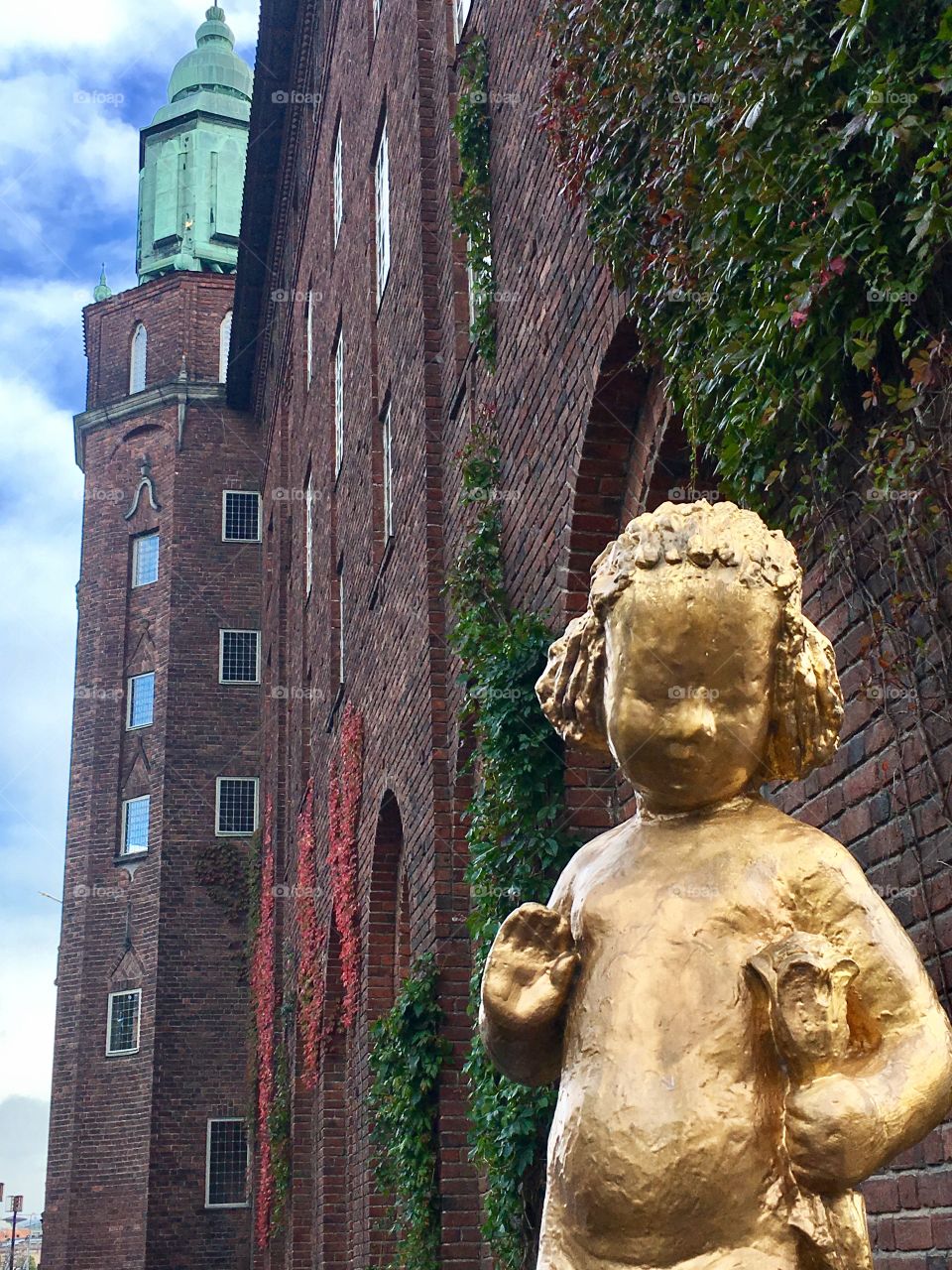Looking up at an old brick building, with a gold statue of a child 
