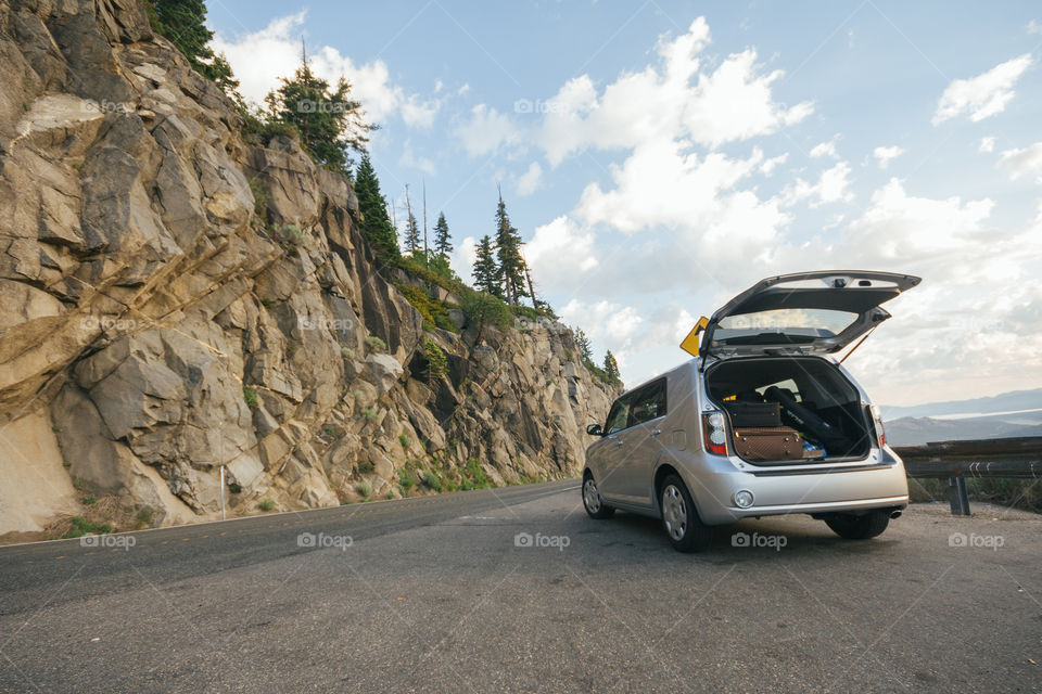 Pulled over car with open trunk on side of road in the mountains 