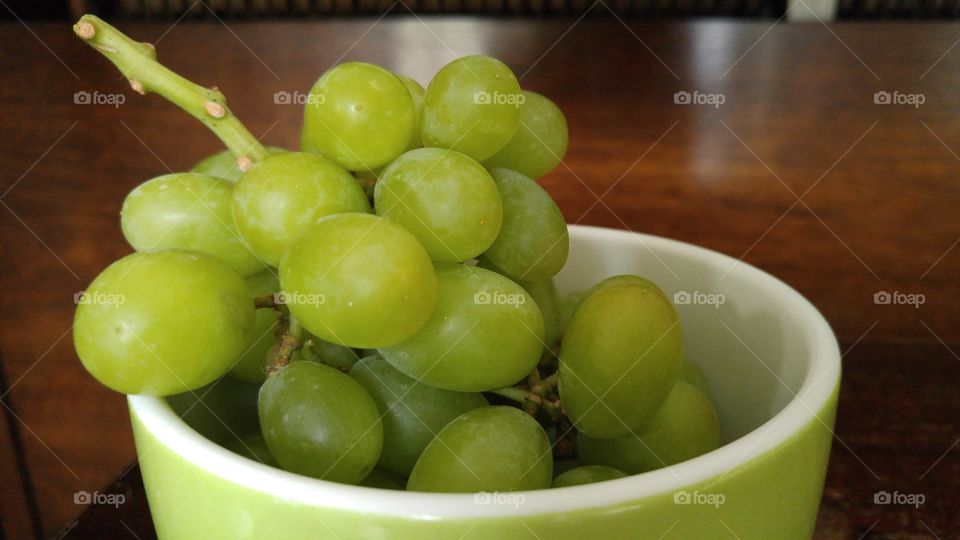 Green grapes in a green and white bowl.