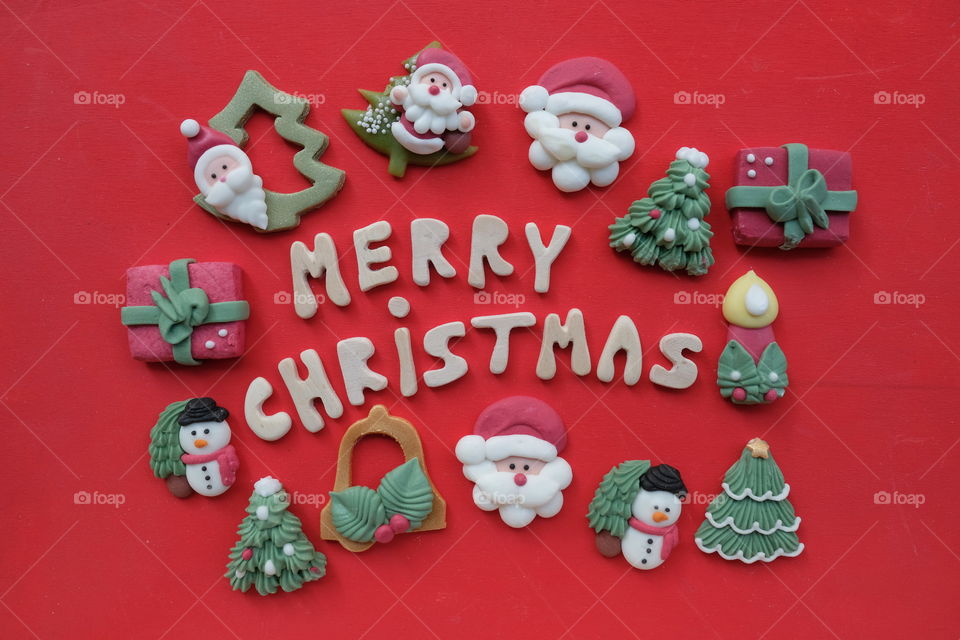 Creative Merry Christmas, with wooden letters and marzipan Christmas symbols over red color background