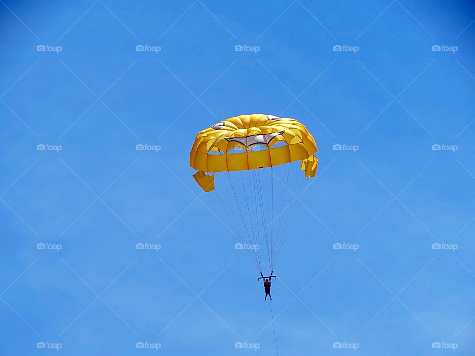 Person parasailing against blue sky