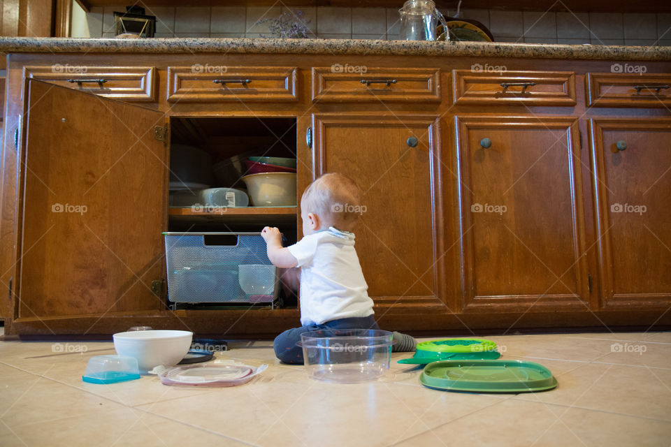 Baby removing container from kitchen cabinet